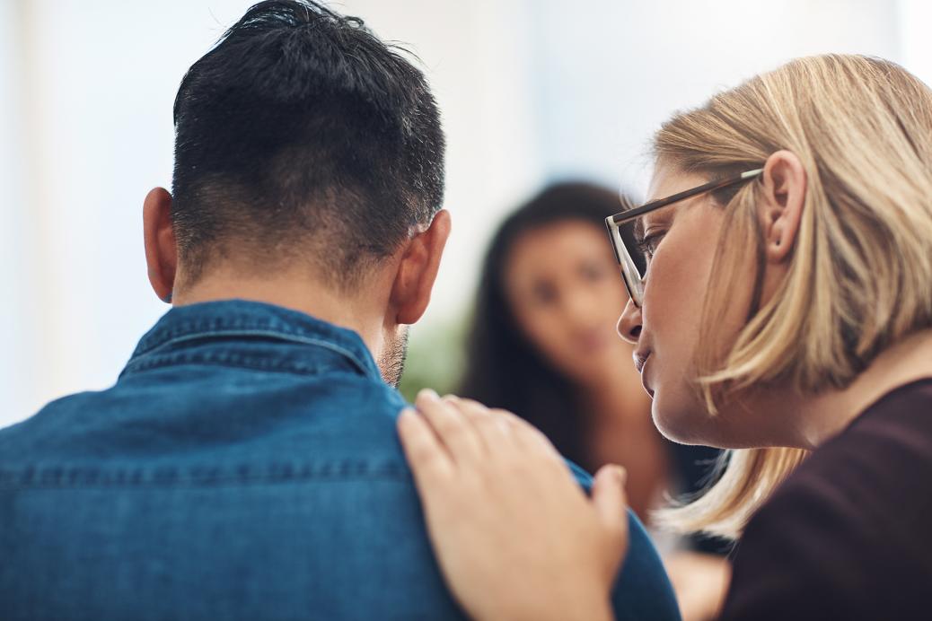 Woman offering comfort with hand on man's shoulder