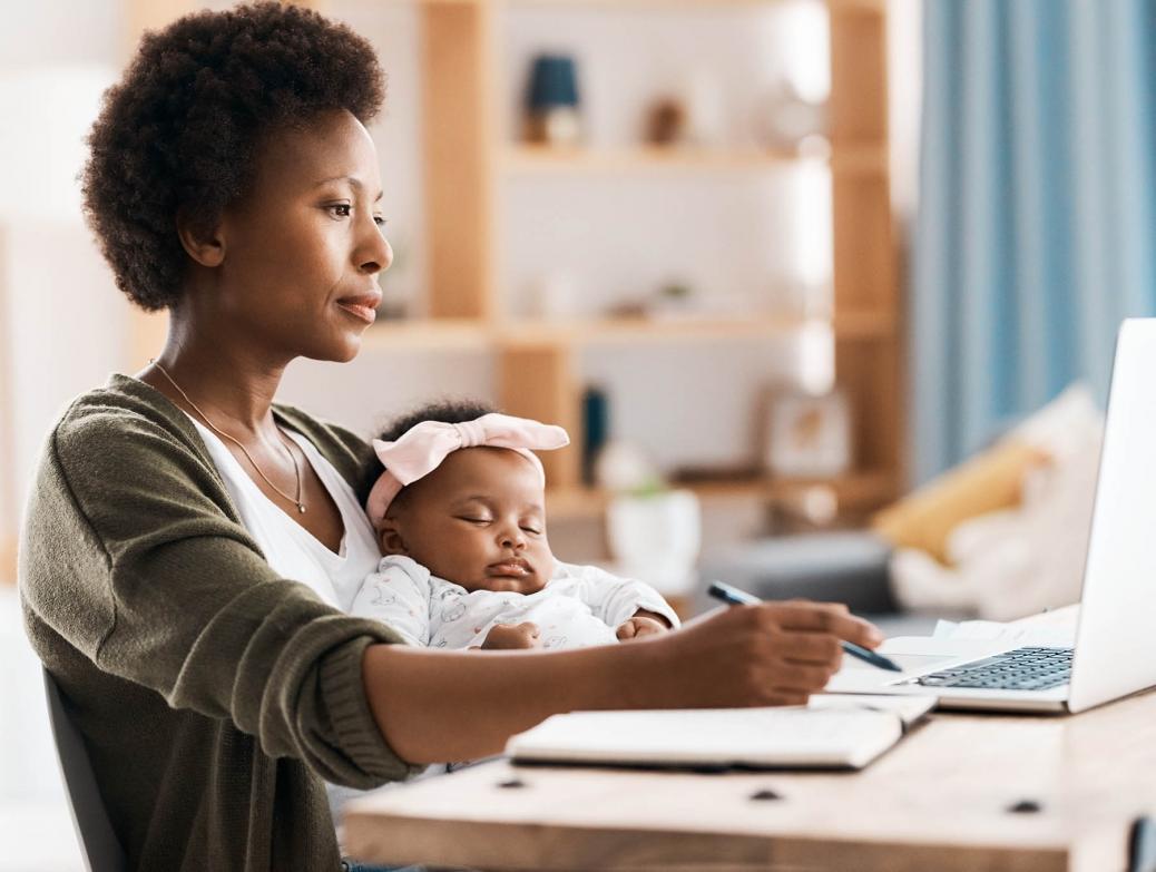 Une maman écrit dans son journal avec son bébé sur les genoux.