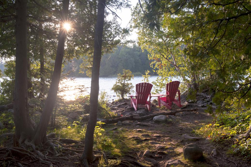 Cadre paisible dans les bois avec deux chaises vides regardant vers le lac.
