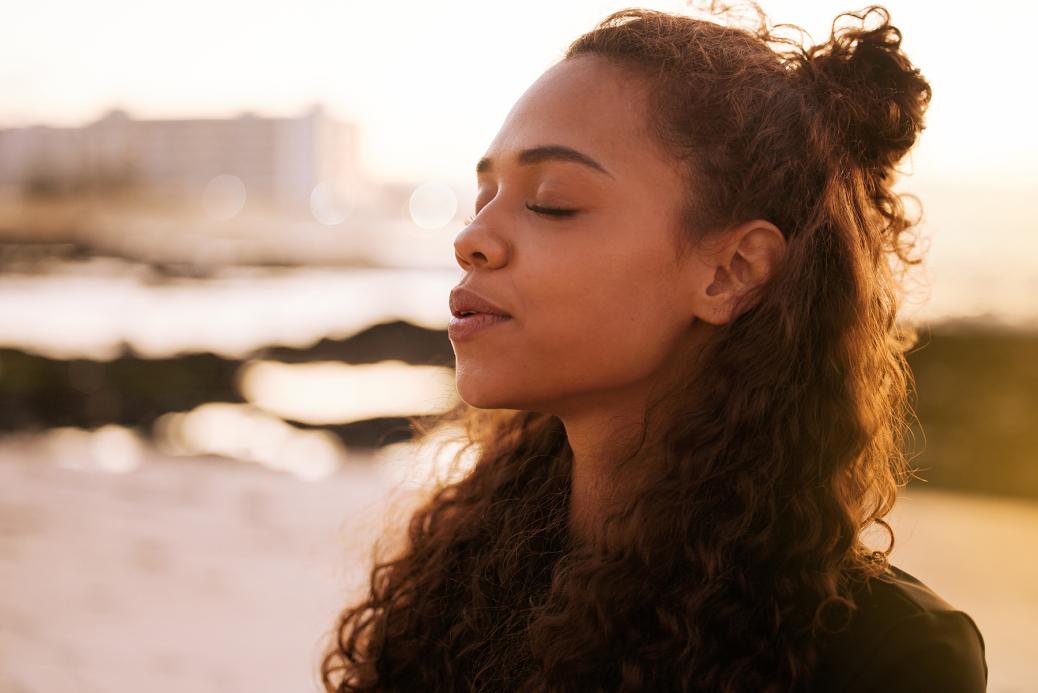 Femme aux yeux fermés prenant une profonde inspiration