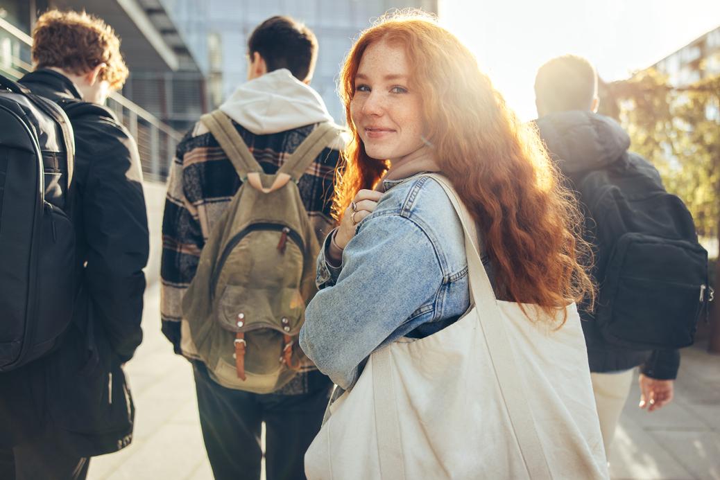 Une étudiante qui marche en groupe et jette un coup d'œil en arrière alors qu'elle se rend en classe à l'université. 