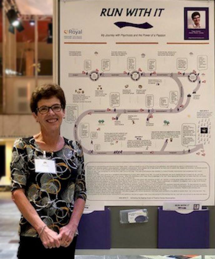 Peggy Hickman à la conférence de 2019 de l’ISPS aux Pays-Bas debout à côté d'une affiche qu'elle a créée.