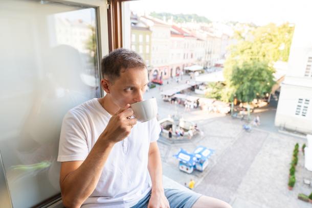 Un homme avec un café près d'une fenêtre ouverte