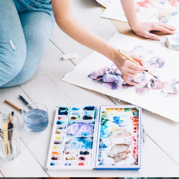 Personne assise sur le sol peignant à l'aquarelle