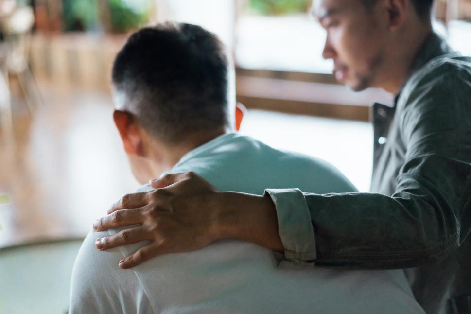 Un homme qui console un autre homme avec une main sur l'épaule