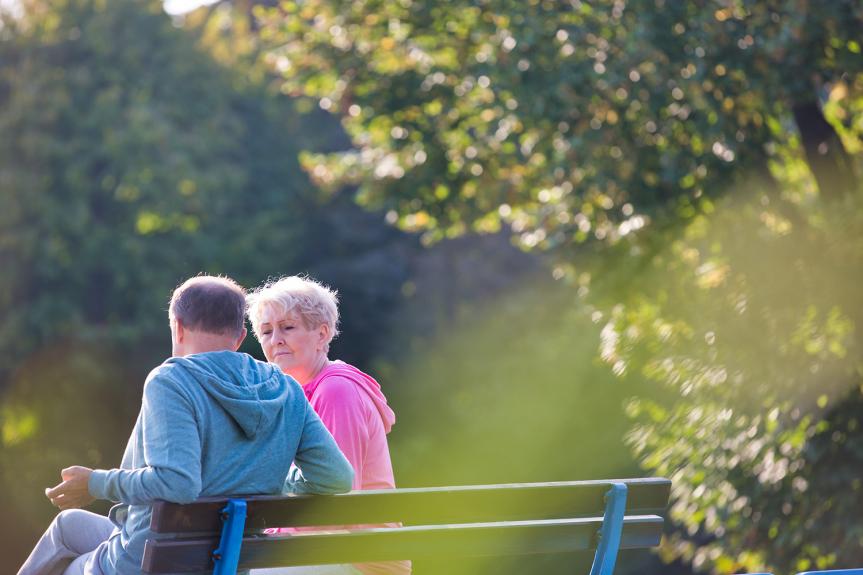 Un homme et une femme assis sure un banc à l'extérieur