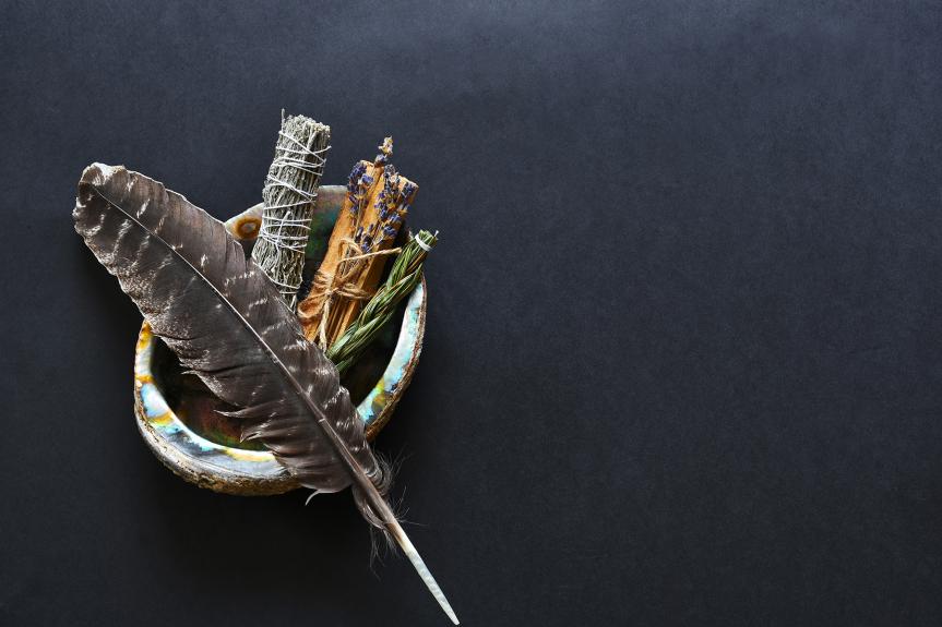 Une plume avec du foin d'odeur, de la sauge, du cèdre et du tabac dans une coquille