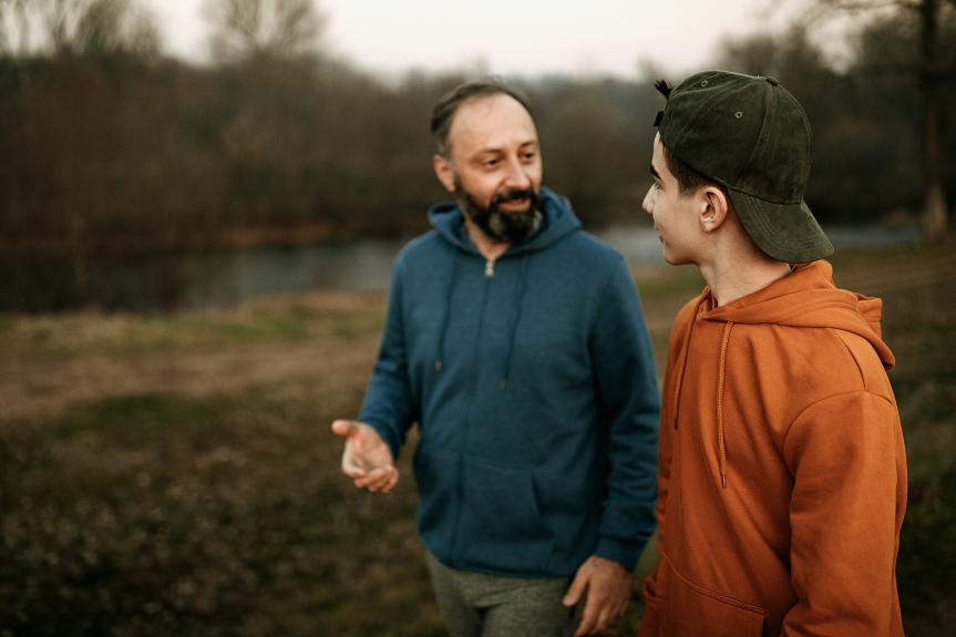 Un homme parle avec un adolescent alors qu'il se promène dans un parc.