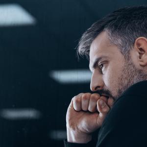 Man biting his finger on clenched fist hand
