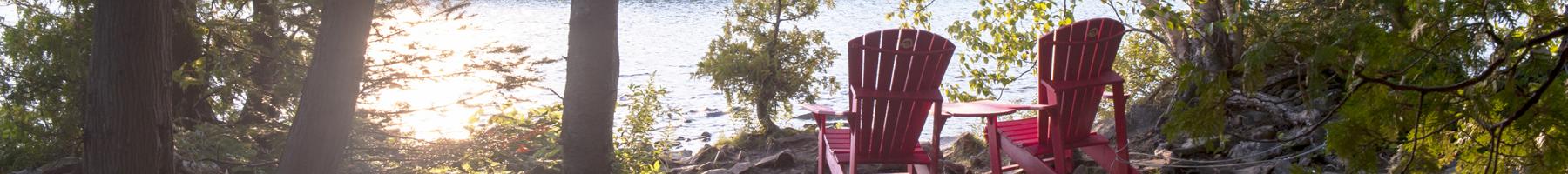 Cadre paisible dans les bois avec deux chaises vides regardant vers le lac.