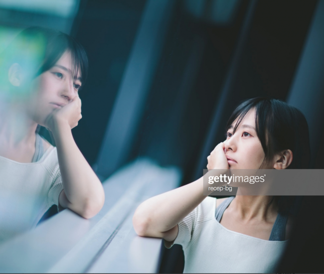 Femme regardant son reflet dans une fenêtre