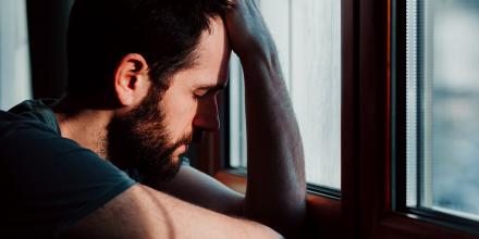 Man leaned over with head in hand looking out window